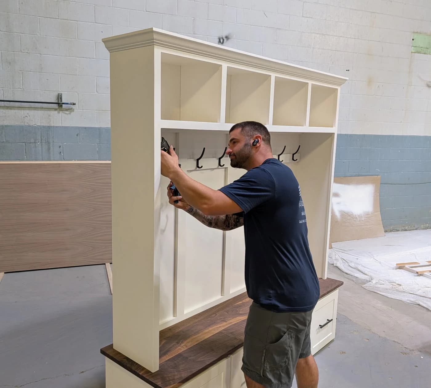 A maker fitting hooks to a freshly painted hall tree in the workshop.